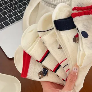 Gros plan de chaussettes blanches en maille avec rayures et broderie ourson