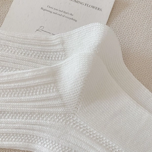 Macro shot of white knit mesh socks featuring breathable texture and fine craftsmanship