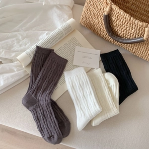 Detail of cable knit crew socks in grey, white, and black with breathable mesh texture