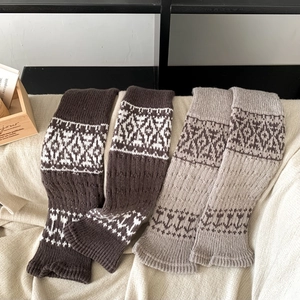 Detail of Fair Isle knit leg warmers with Nordic patterns in brown and beige colors