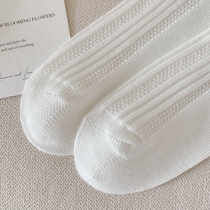 Detail shot of white knitted cotton socks showing mesh texture and rib knit pattern