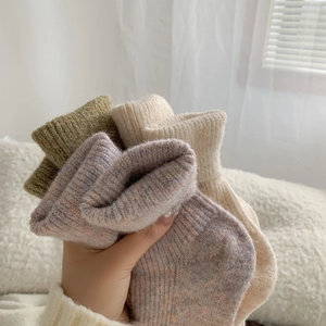 Close-up of thick wool blend socks in green, purple, and cream with high ribbed cuffs