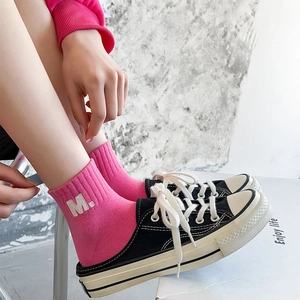 Detail of pink cotton mid-calf sock with white M embroidery and ribbed cuff texture