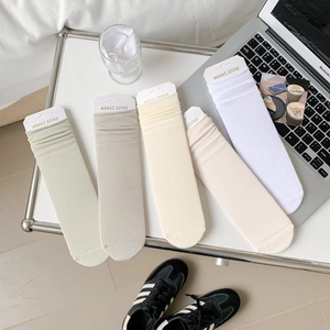 Flat lay of five pairs of ribbed cotton slouch socks in various pastel colors