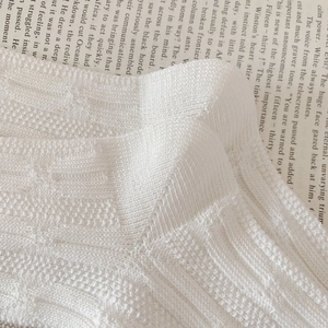 Close-up of white knit socks with 3D diamond pattern and textured cotton weave