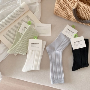 Detail of four-color ribbed mesh socks set in green, white, gray and black with tags
