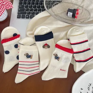 Détail de chaussettes en coton blanc avec broderie chien et pois rouges dans un cadre cosy