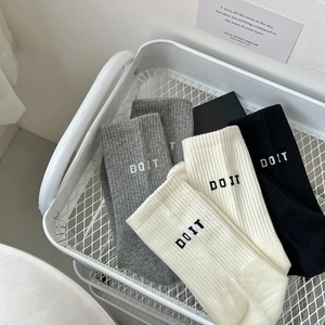 Detail of ribbed knit crew socks with DO IT lettering in gray, beige and black
