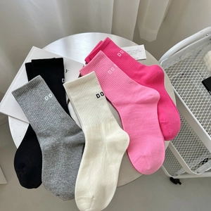 Detail of five assorted cotton crew socks with 'DO' letter embroidery on a white table