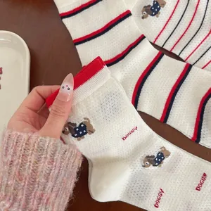 Détail d'une chaussette en coton crème avec rayures rouge et bleu et broderie chien