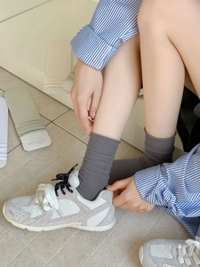 Detail of ribbed cotton mid-calf socks in grey, sage green, and off-white colors
