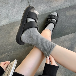 Detail of gray mid-calf ribbed socks with white DO letter embroidery and black platform sandals