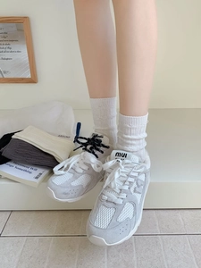 Close-up of stylish mesh knit crew socks paired with fashion sneakers and MIU brand logo