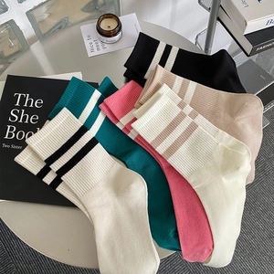 Flat lay of colorful striped mid-calf socks set on a silver table with lifestyle props