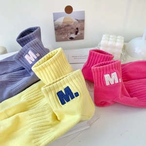 Detail of vibrant M letter embroidery on colorful cotton sports socks in pink and yellow