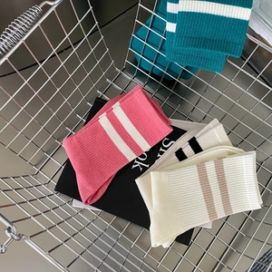 Detail of ribbed knit mid-calf socks in pink, green, and white inside a metal basket