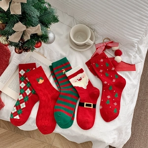 Flat lay of five assorted red and green Christmas socks on a white textured blanket