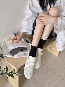 Detailed knit texture of cable knit mid-calf socks in black, white, cream and grey