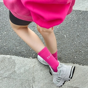 Close-up of bright rose pink mid-calf socks with white 'DO IT' text and dad sneakers