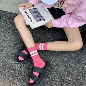 Close-up of pink mid-calf cotton socks featuring double white stripes in a sporty style
