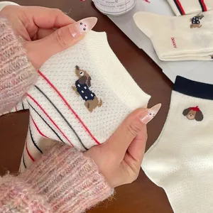 Détail d'une chaussette en coton avec broderie chien et bord-côte rayé sur un bureau