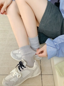 Close-up of light grey ribbed knit crew socks with breathable mesh texture on model