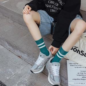 Close-up of green mid-calf crew socks with white stripes worn with retro sneakers
