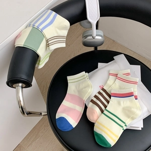Detailed shot of striped cotton ankle socks in beige with colorful ribbed cuffs on a chair