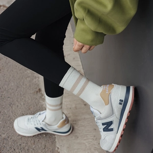 Close-up of cream knit mid-calf socks with brown stripes in a sporty outdoor setting