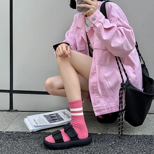 Close-up of pink striped crew socks paired with black platform sandals and denim jacket