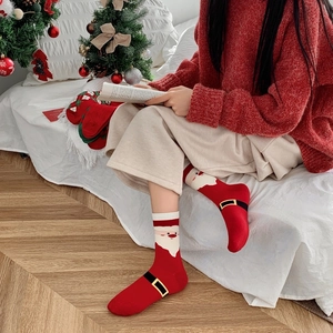 Close-up of red Christmas socks with Santa Claus pattern worn in a cozy festive setting