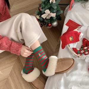 Detail of red and green striped Christmas socks with reindeer embroidery and gift box