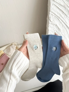 Close-up of ribbed cotton crew socks with colorful embroidered smiley face detailing