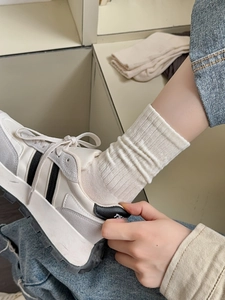 Detail of white ribbed cotton crew socks paired with retro suede and fabric sneakers