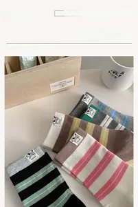 Détail de chaussettes rayées en coton avec étiquettes de chien et texte LUCKY