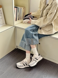Close-up of white ribbed crew socks paired with vintage sneakers and denim jeans