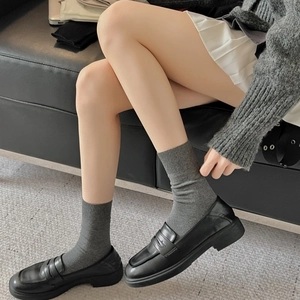 Nahaufnahme der schwarzen Plateau-Loafer und grauen Rippstrick-Socken im modernen Design