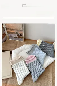 Détail de chaussettes rayées tricotées avec broderie cœur en bleu, rose et gris
