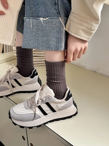 Detail of white sporty sneakers with gray suede panels and brown ribbed mid-calf socks