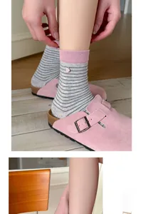 Detail of striped cotton socks with pink ribbed cuffs and handmade label on a warm floor