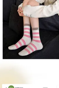 Détail de chaussettes en coton rayées grises avec patch chien lucky et revers marron