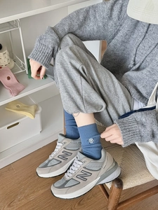 Detail of blue crew socks with smiley embroidery worn with grey sneakers and casual wear