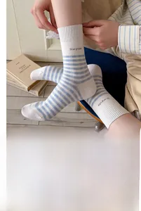 Détail de chaussettes en coton rayées crème et bleu clair avec texte Simple sur le revers