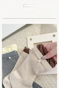Detail of soft ribbed crew socks with pearl accents on white knitted blanket