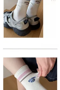 Detail of white cotton rib socks showing blue 'DELIGHT' embroidery and colored stripes