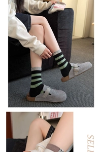 Détail de chaussettes à rayures avec broderie chiot portées avec des mules en daim gris