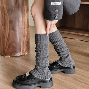 Dettaglio di scaldamuscoli in maglia grigio scuro con strisce verticali e design a pieghe