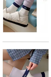 Detail of color-block knit socks with lettering paired with white leather loafers