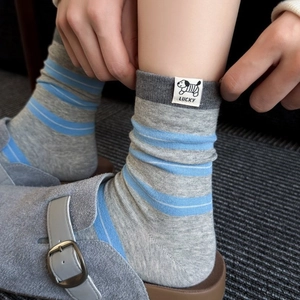 Chaussettes mi-mollet grises à rayures bleues avec écusson chien mignon sur un tapis doux