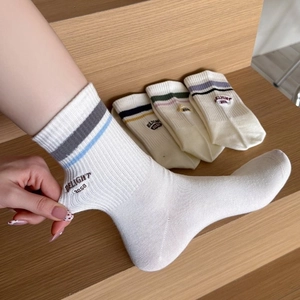 White cotton mid-calf socks with rib knit texture and colorful stripes with embroidery